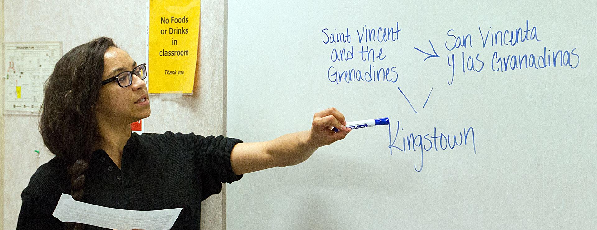 Student explaining on white board translation of English words to Spanish