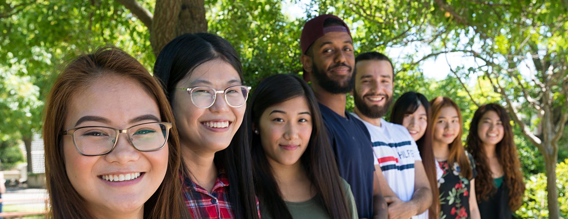 Students of various ethnicities taking group picture outside