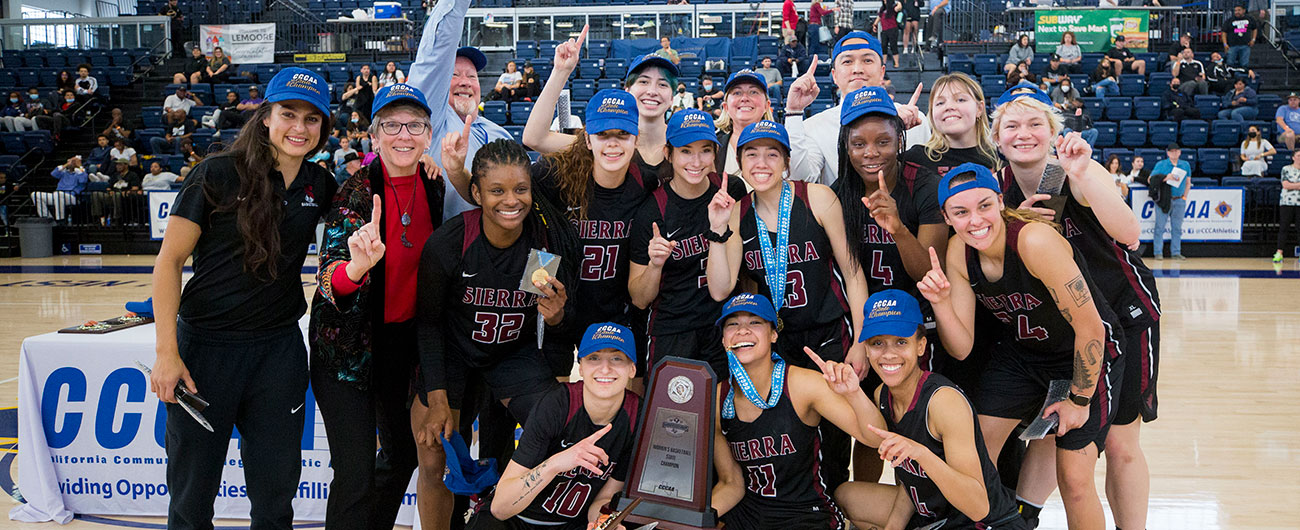 Group photo of 17 people, including Sierra Women's basketball team and coaches with their trophy.