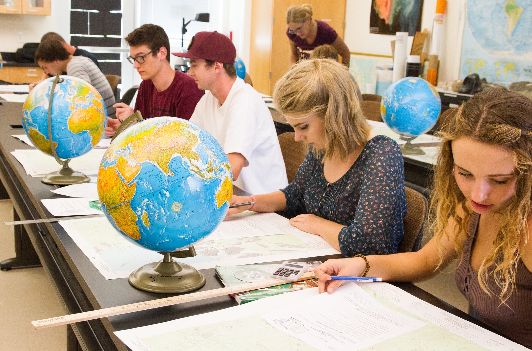 Students at table studying globes in class.