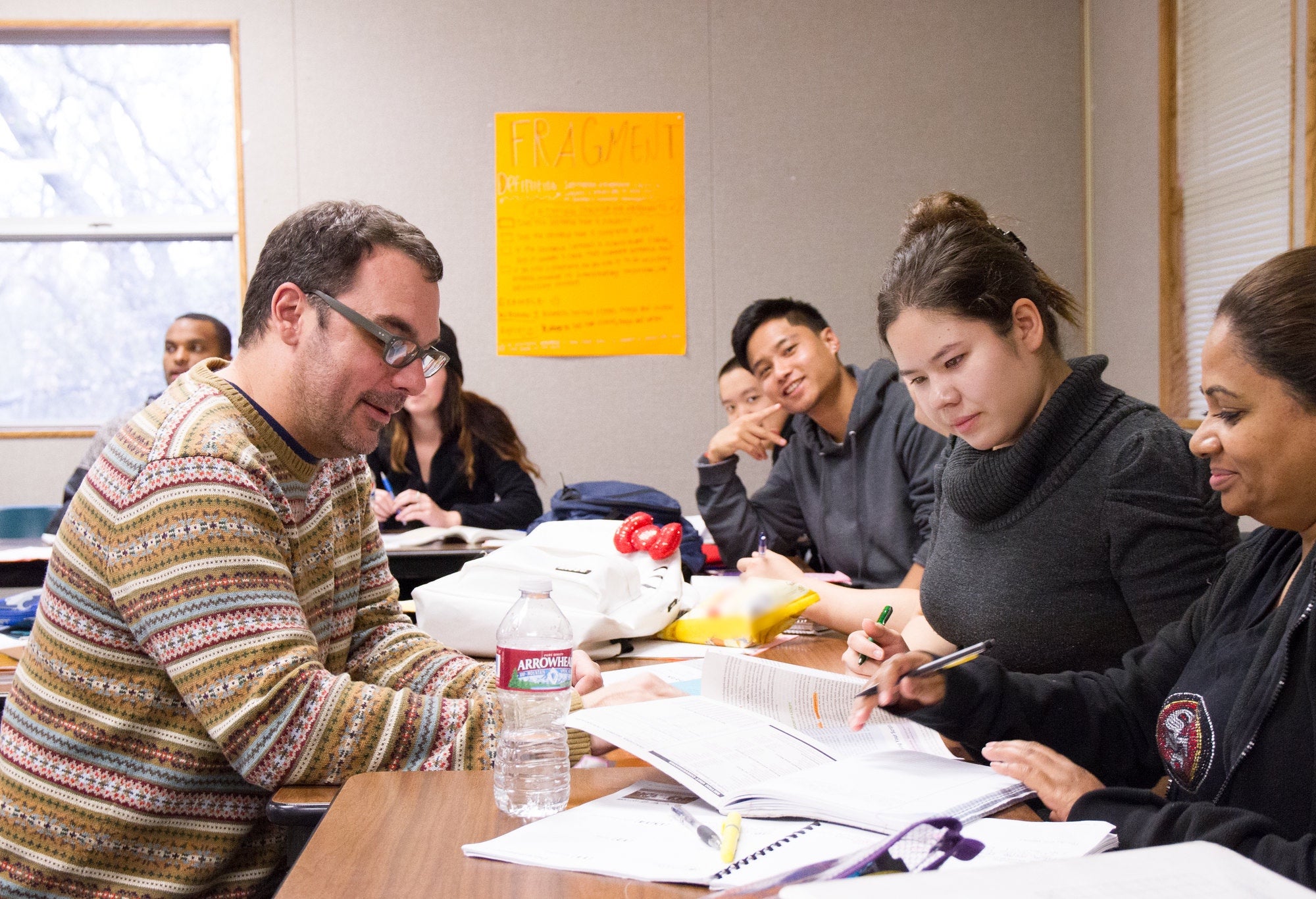 Students working with professor on assignment in English class.