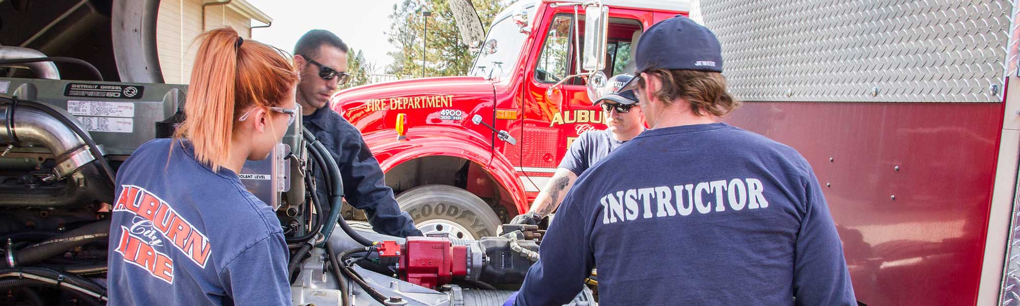 Fire Tech instructor and students inspect fire engine machinery