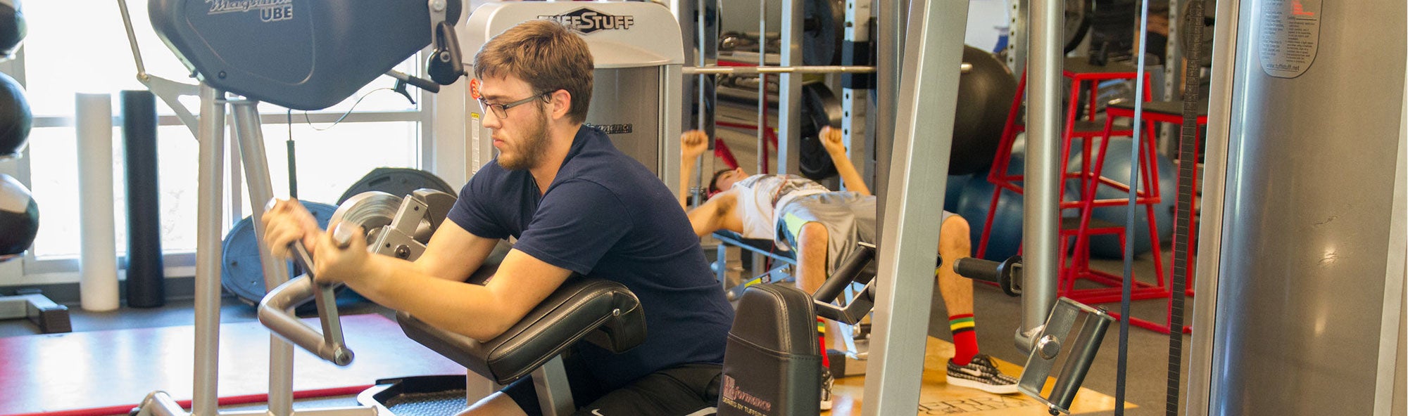 Student in weight room using weights.