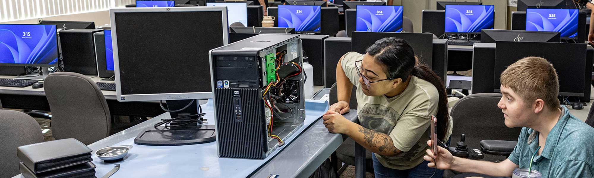 Two students wiring the inside of a computer