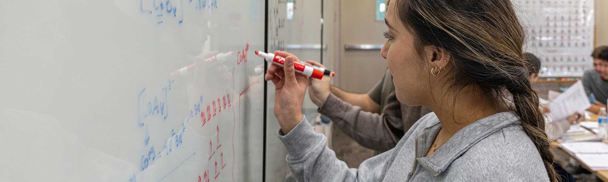 Student using white board to figure out math problem