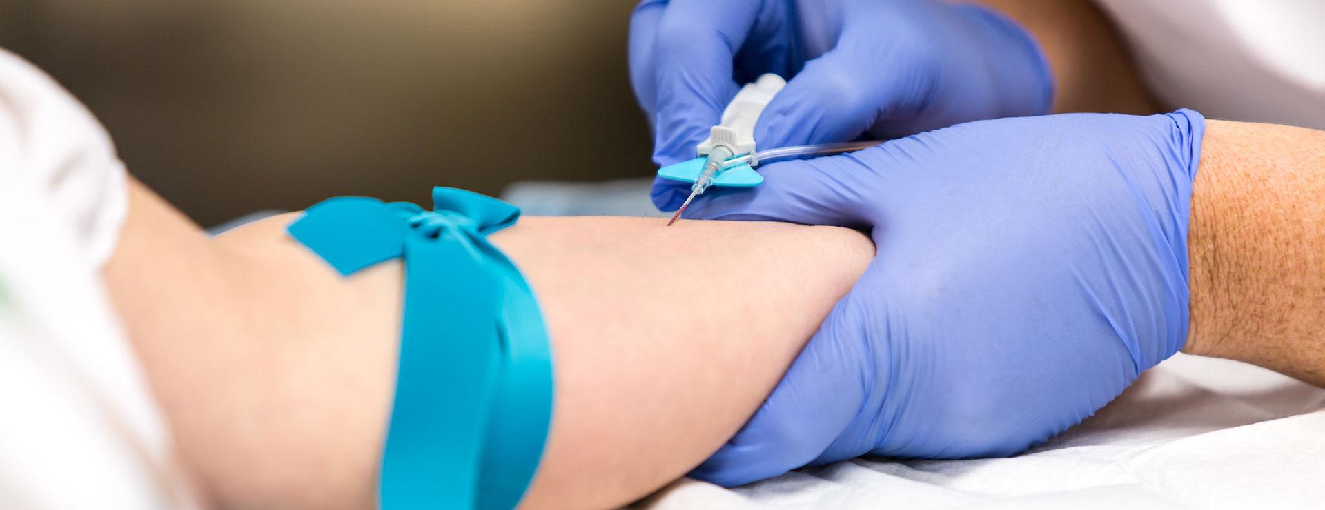 Hands of phlebotomy student inserting IV into patient's arm