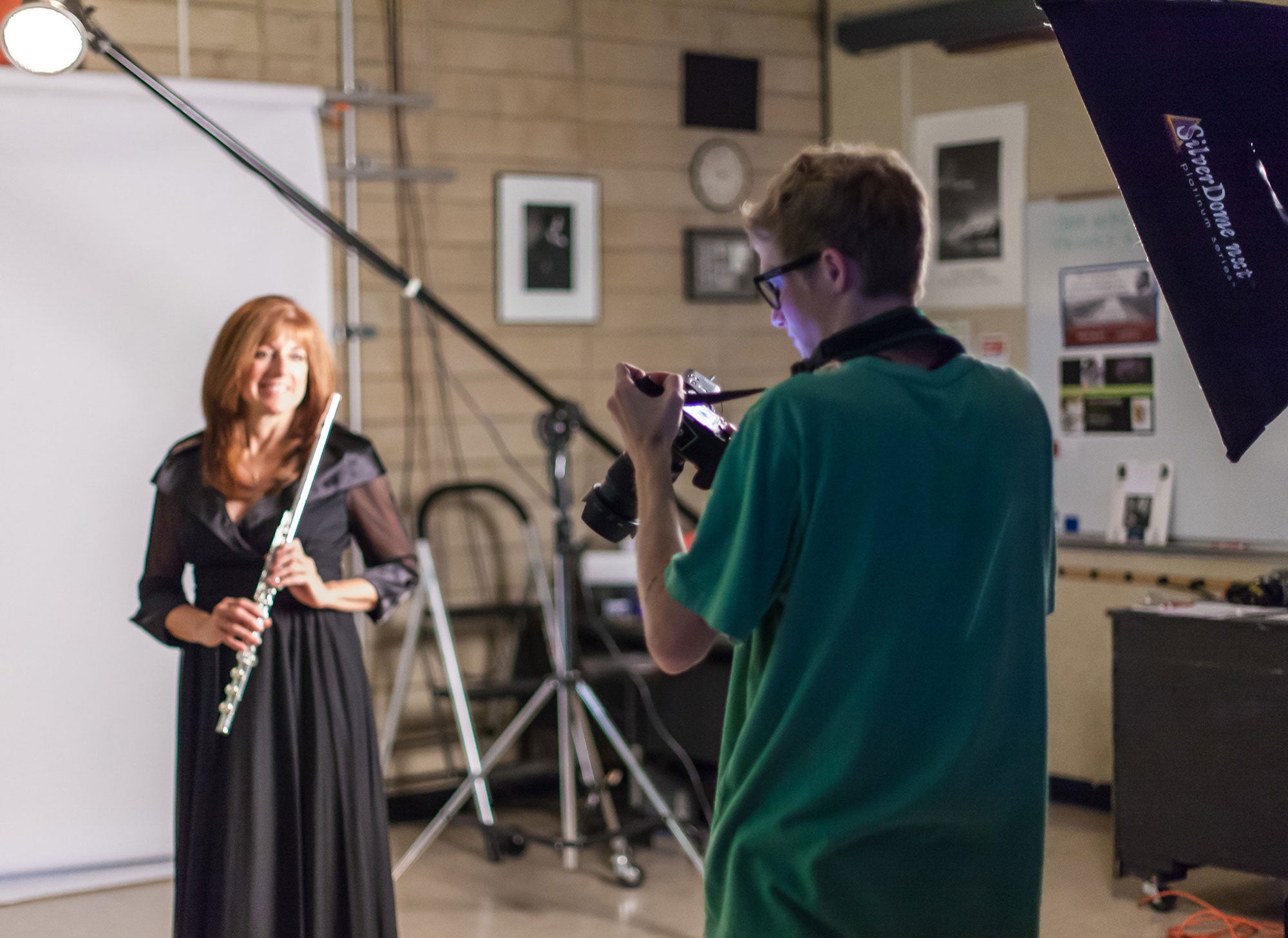 Woman posing in studio with flute for photography student.