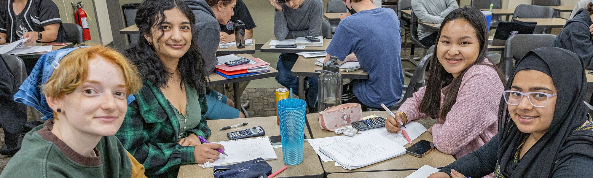 Four students using calculators to problem-solve physics equations