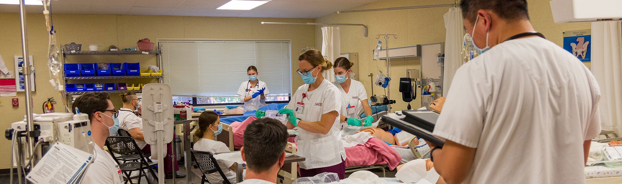 Six students listening to instructor explain a nursing technique