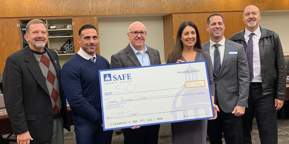Six people pose with oversized check from SAFE Credit Union.
