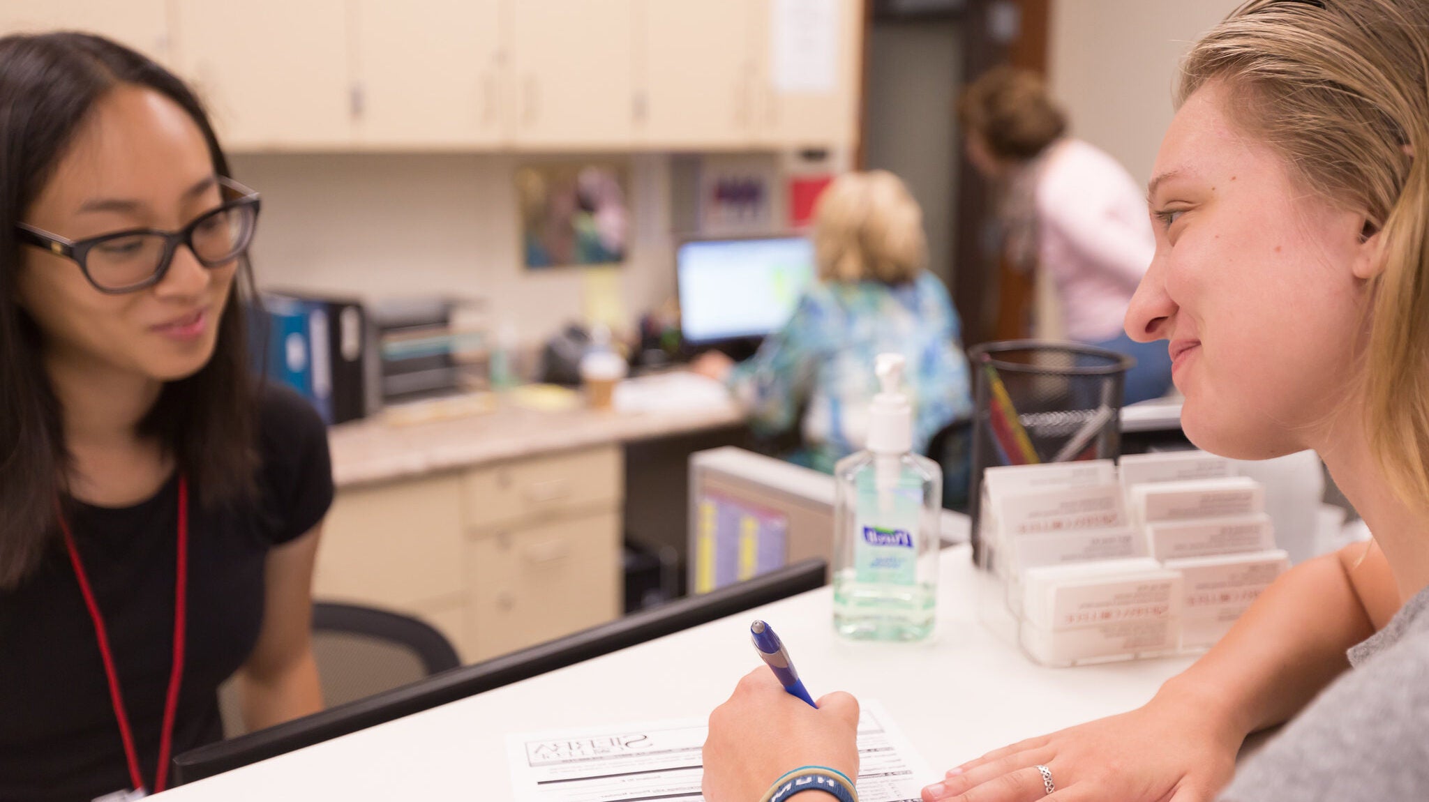 Lady happily filling out intake form at desk