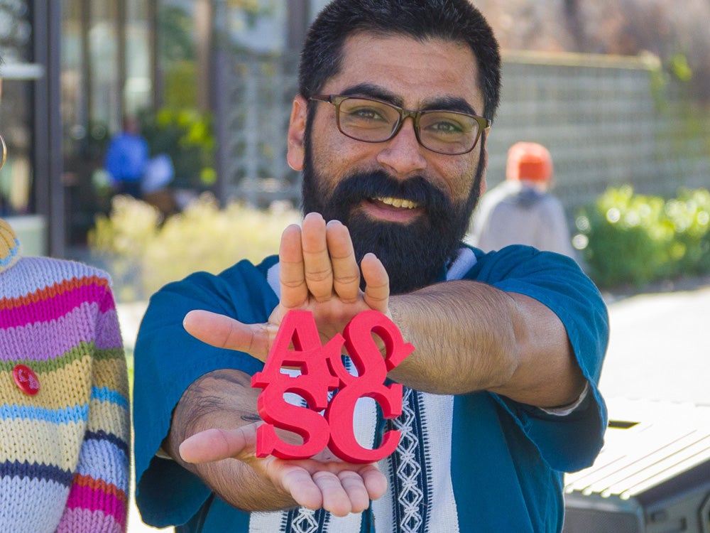 Sierra College staff member holding up ASSC logo at Club Days event