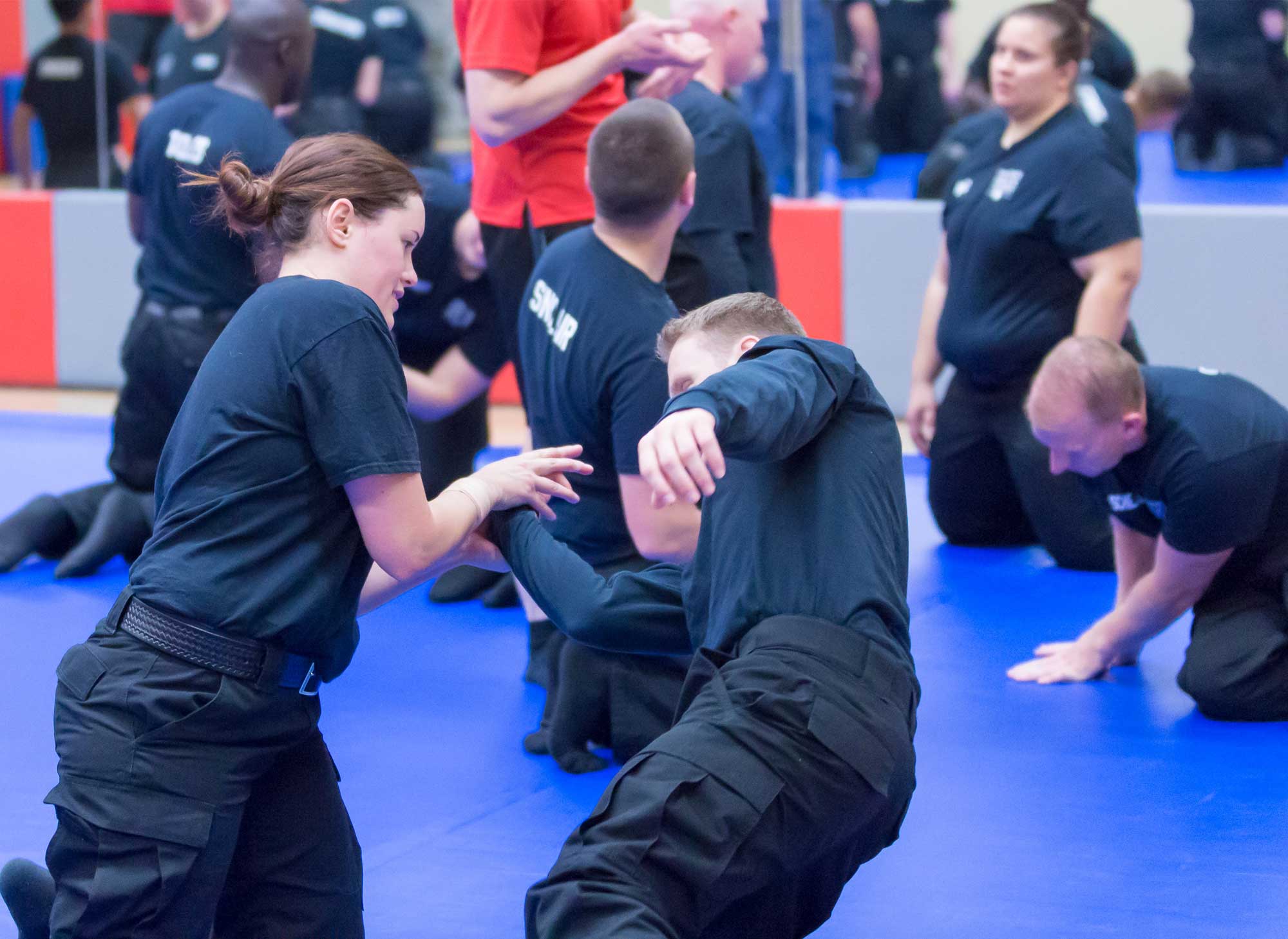Administrative Justice students practicing hand-to-hand combat on a gym floor mat
