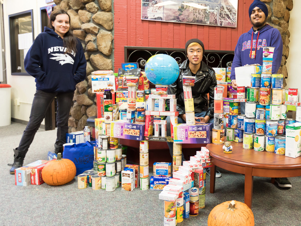 Three students offering canned food on the table