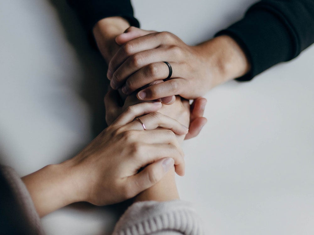 Two persons holding their hands to support each other