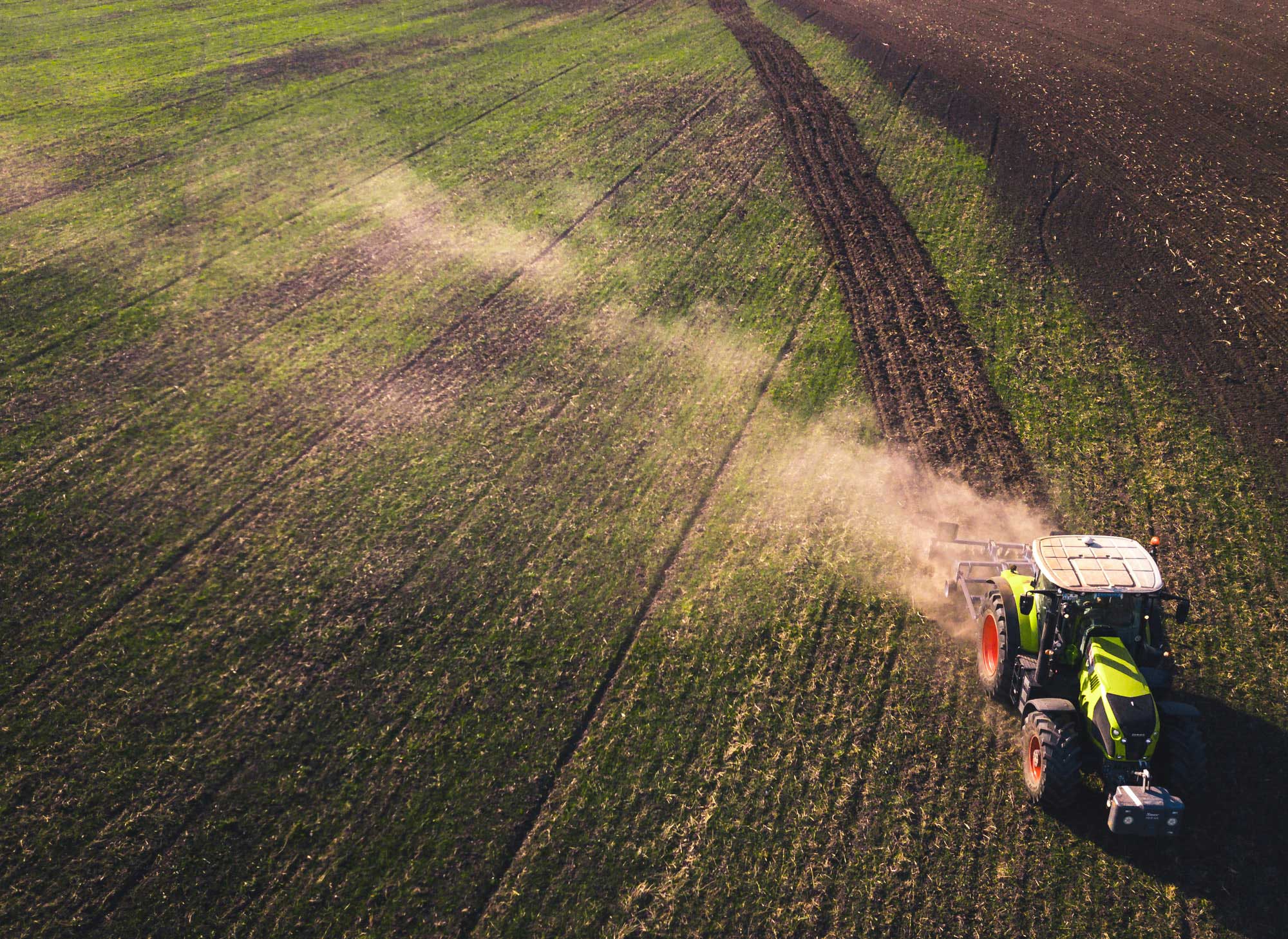 Green tractor plowing large field