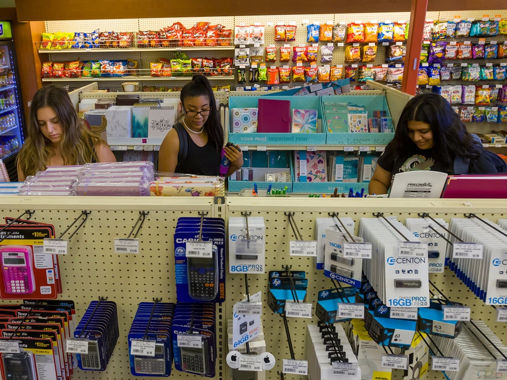 Three students are browsing stuff in the bookstore