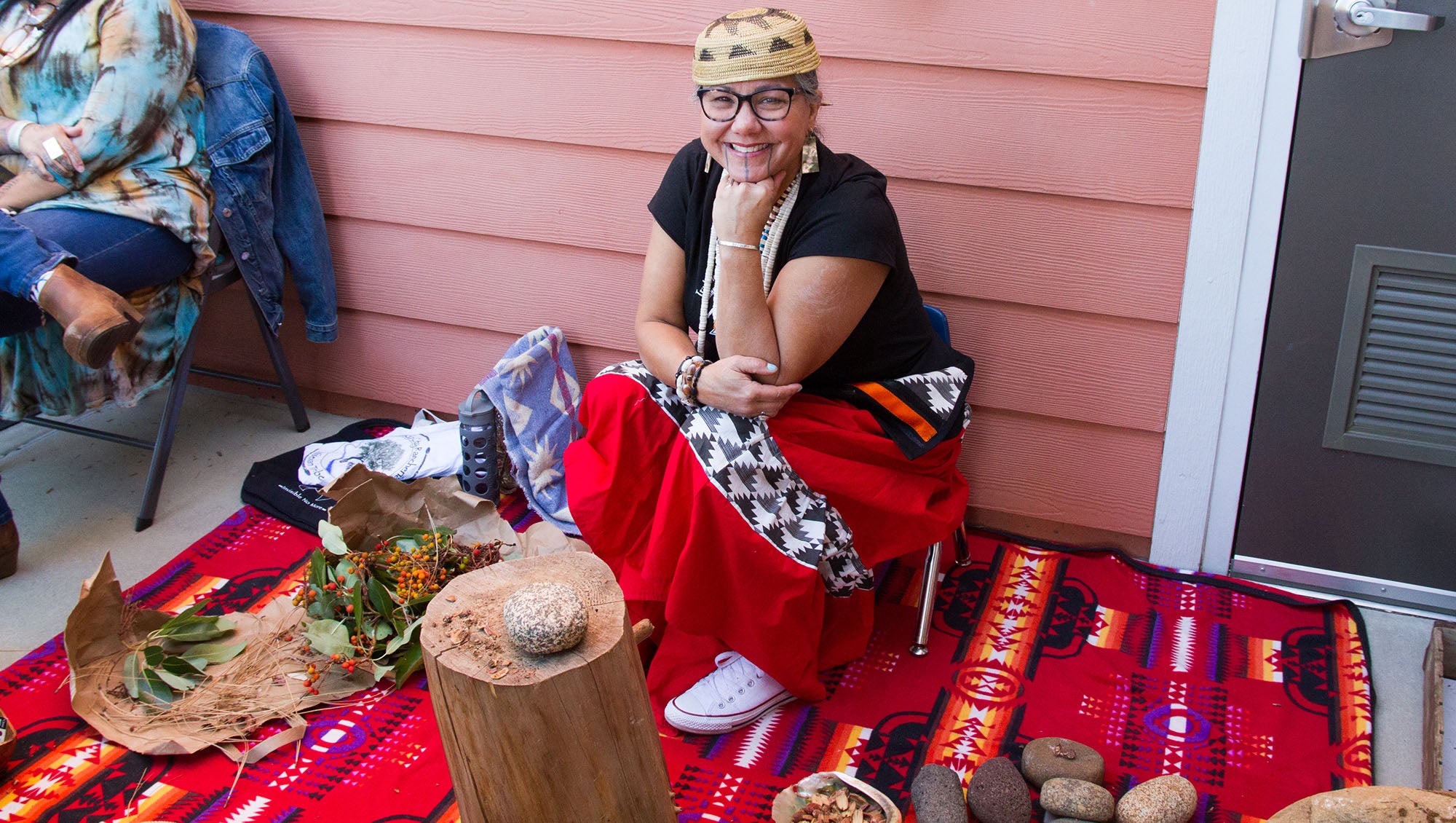 Nisenan Native American woman teaching kids how to string necklaces made from seeds and nuts