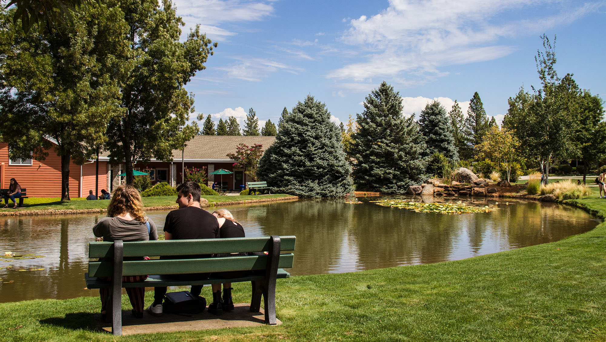 Three students sitting next to the pond on the Sierra College NCC campus