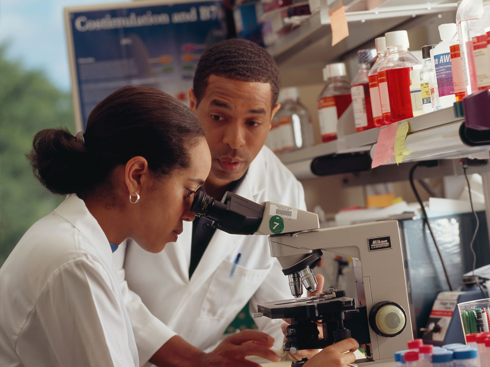A Black man and woman in the lab working with microscope