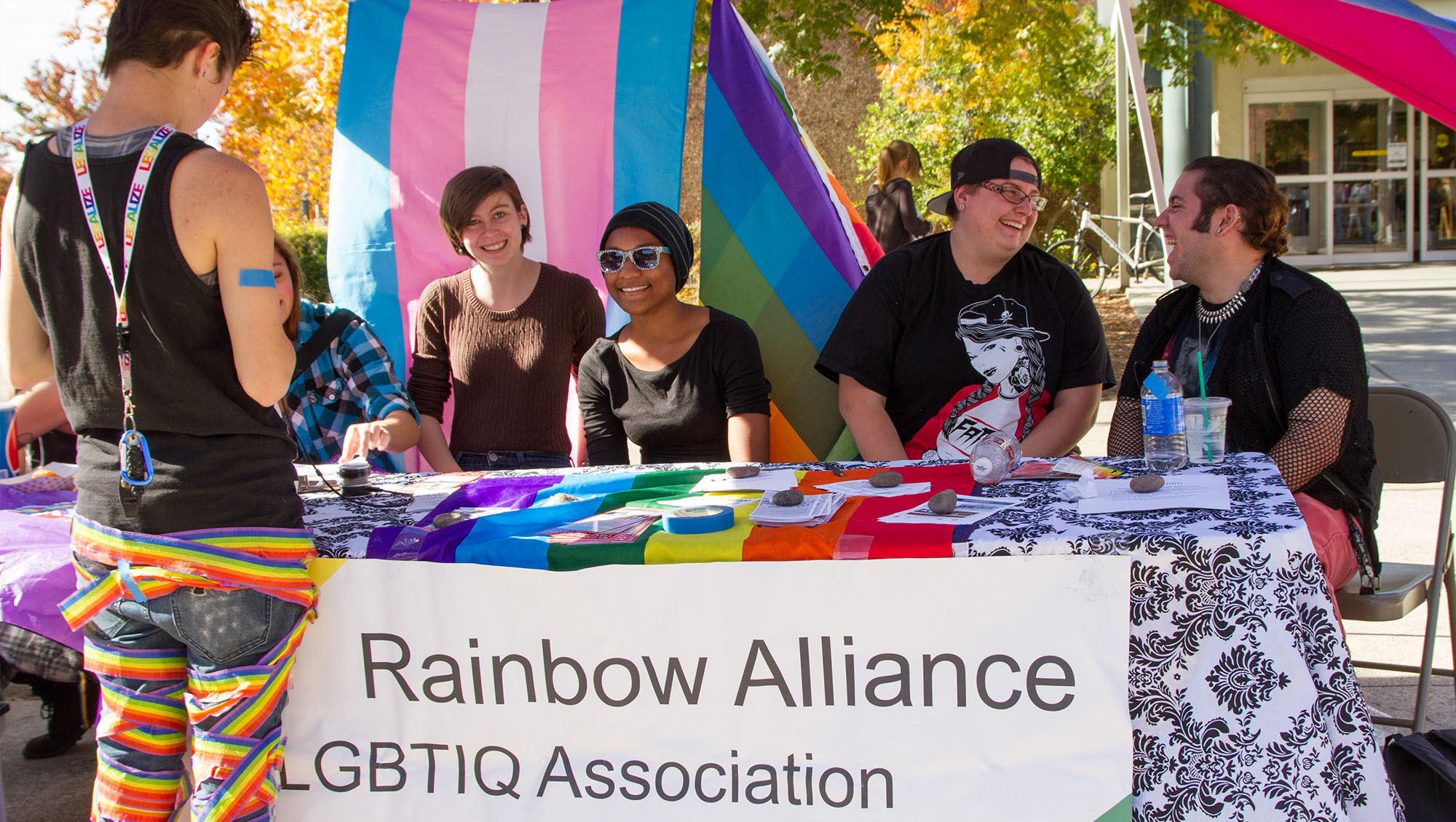 Students welcoming students at Rainbow Alliance booth during Wolverine Week at Sierra College