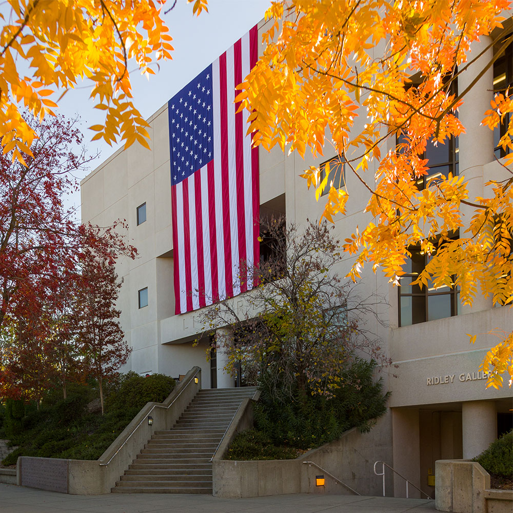 Large United States flag draped down the side of the Sierra College library building during Veterans Day