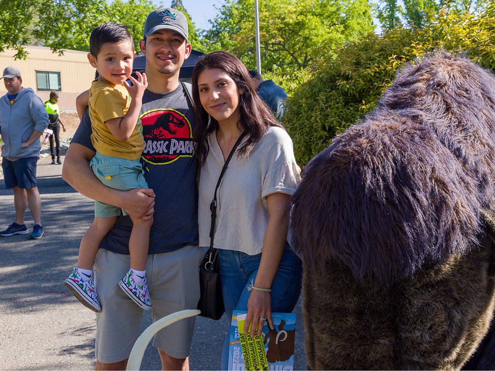 Family taking a picture with large mammoth stuffed animal at Dino Day