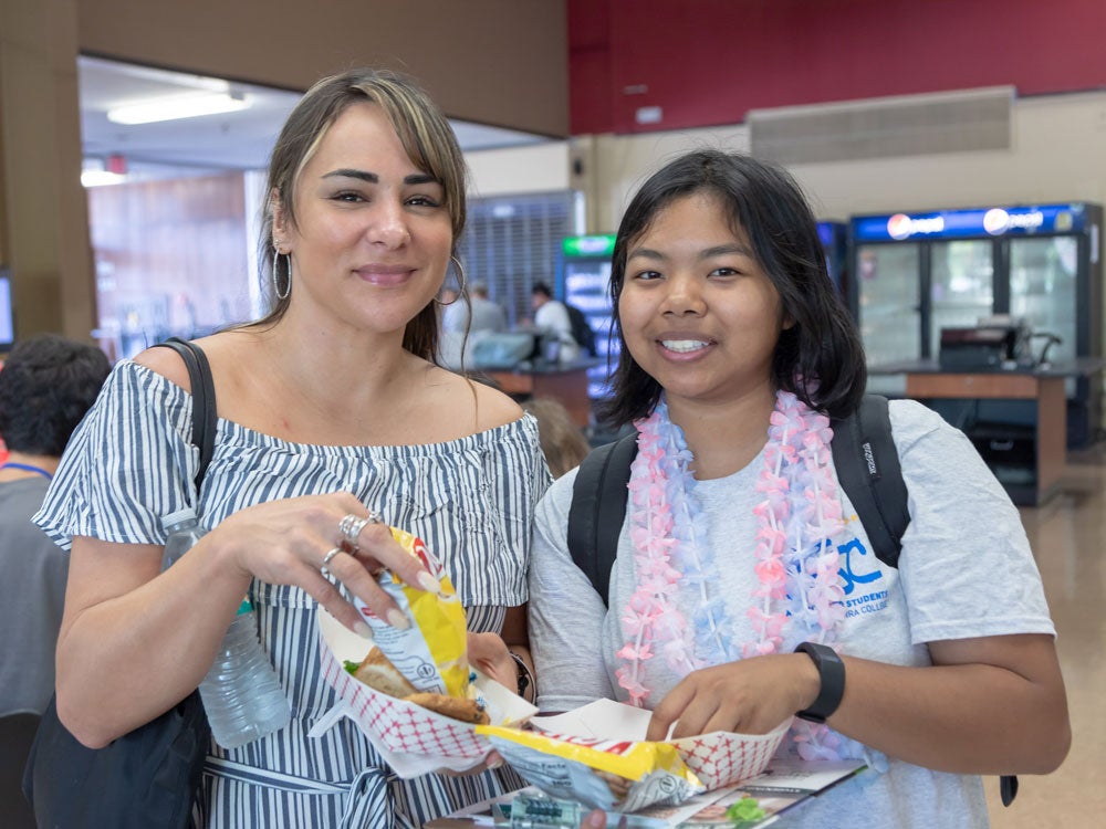 Two students have their food in hand standing in cafeteria
