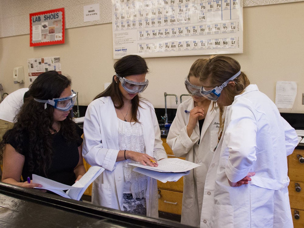 Four chemistry students in the classroom are looking at their papers