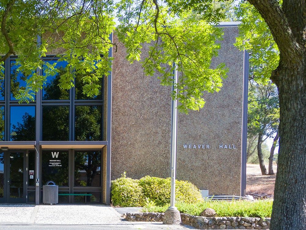 Front of Weaver Hall building with multi-panel glass and landscaping