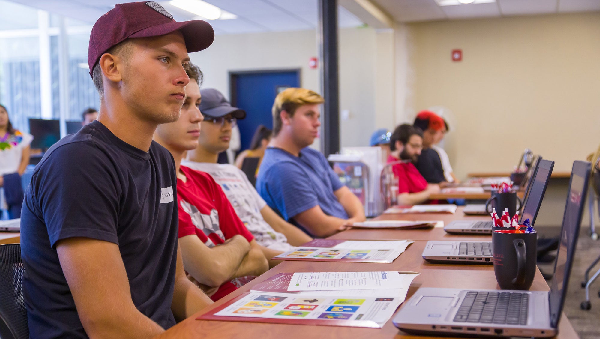 Row of students sitting at desks with laptops listening to Career and Academic Planning instructor.