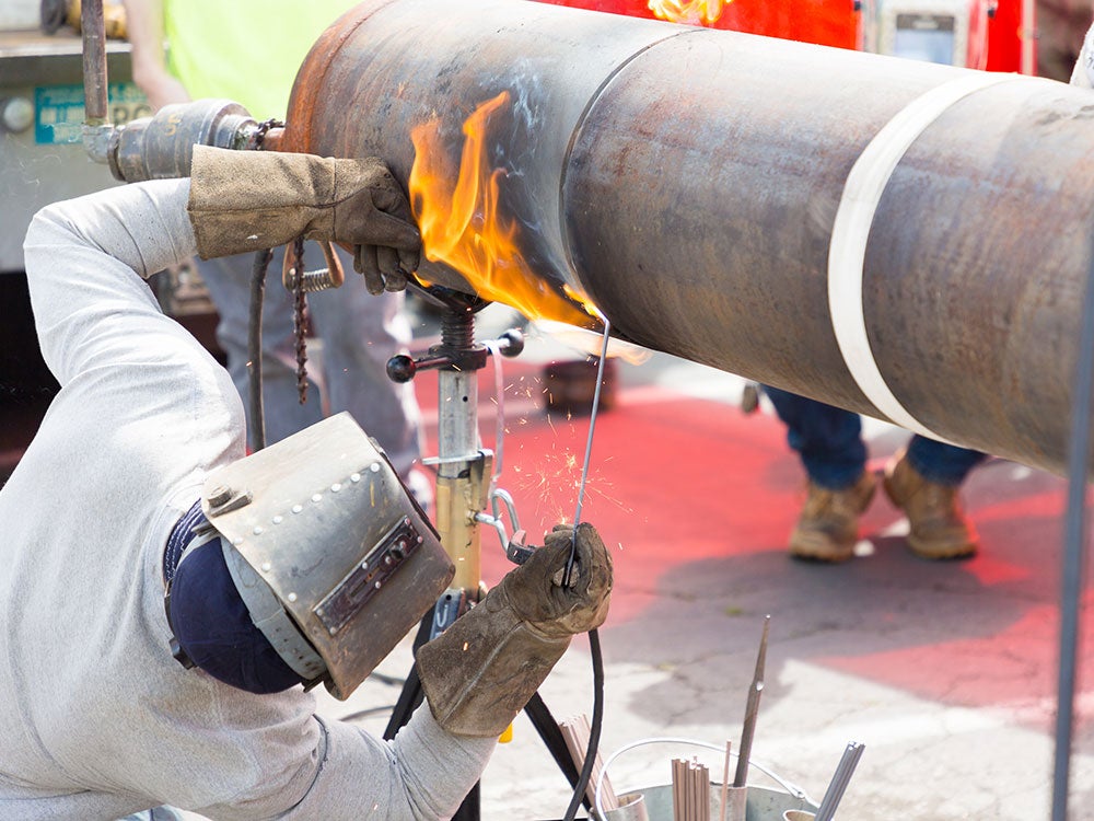 Student uses heat to split steel column while wearing welding protective gear