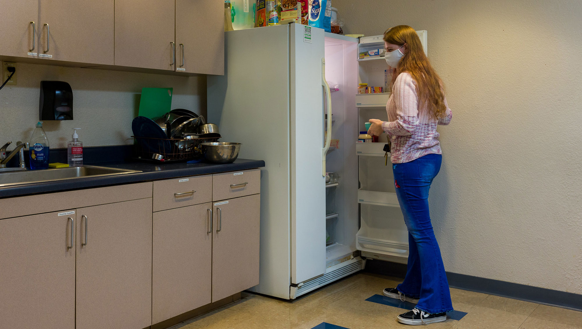Dorm student taking food out of refridgerator in residence hall kitchen