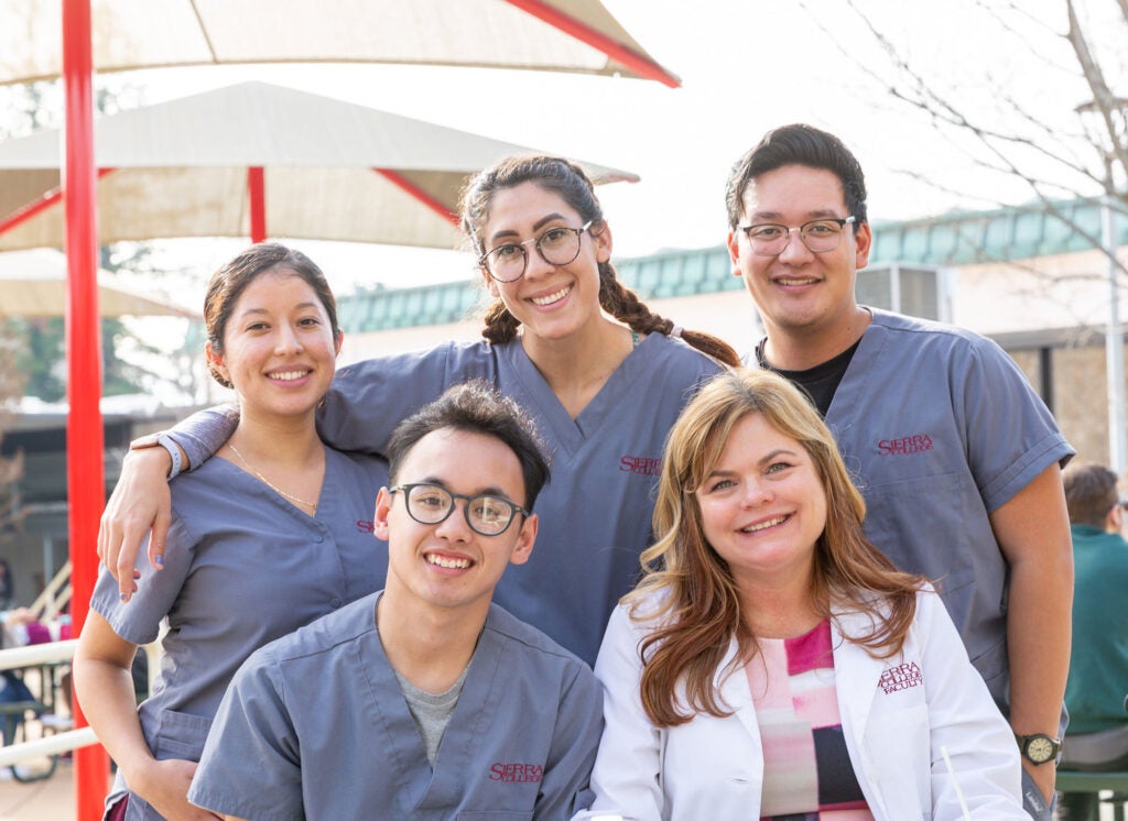 Group shot of two male nursing students and two female allied health students with instructor