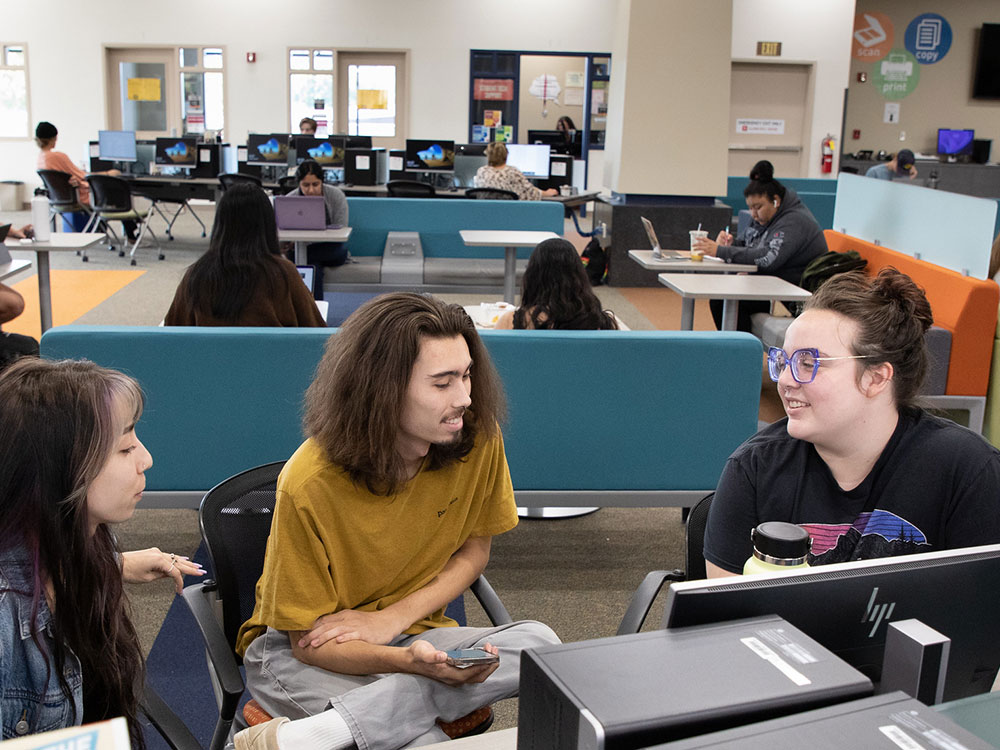 Three students using computer research databases in library on Rocklin campus