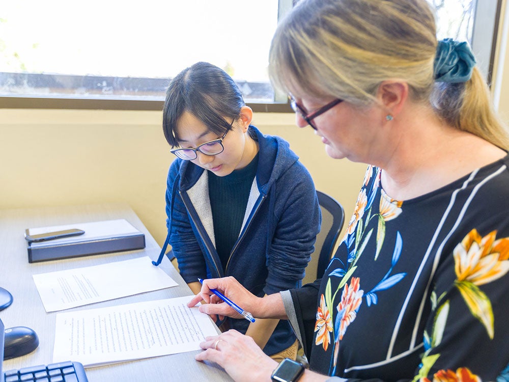 Writing Center staff member assists a student with her essay