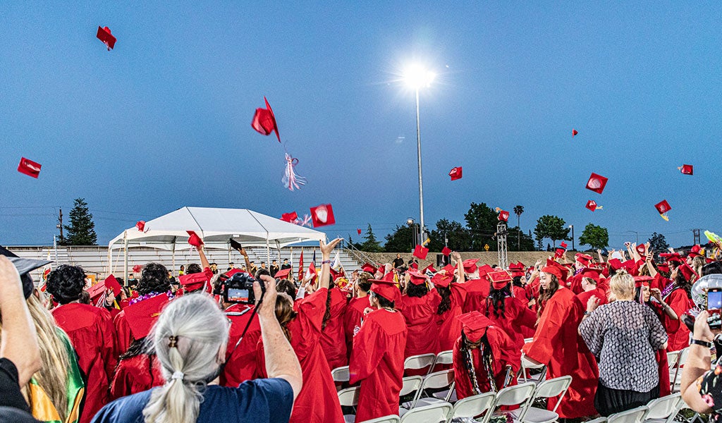 Graduates throw red caps in air in celebration of graduating from Sierra