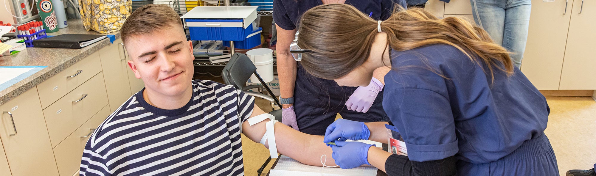 Phlebotomy student practicing drawing blood on a volunteer.