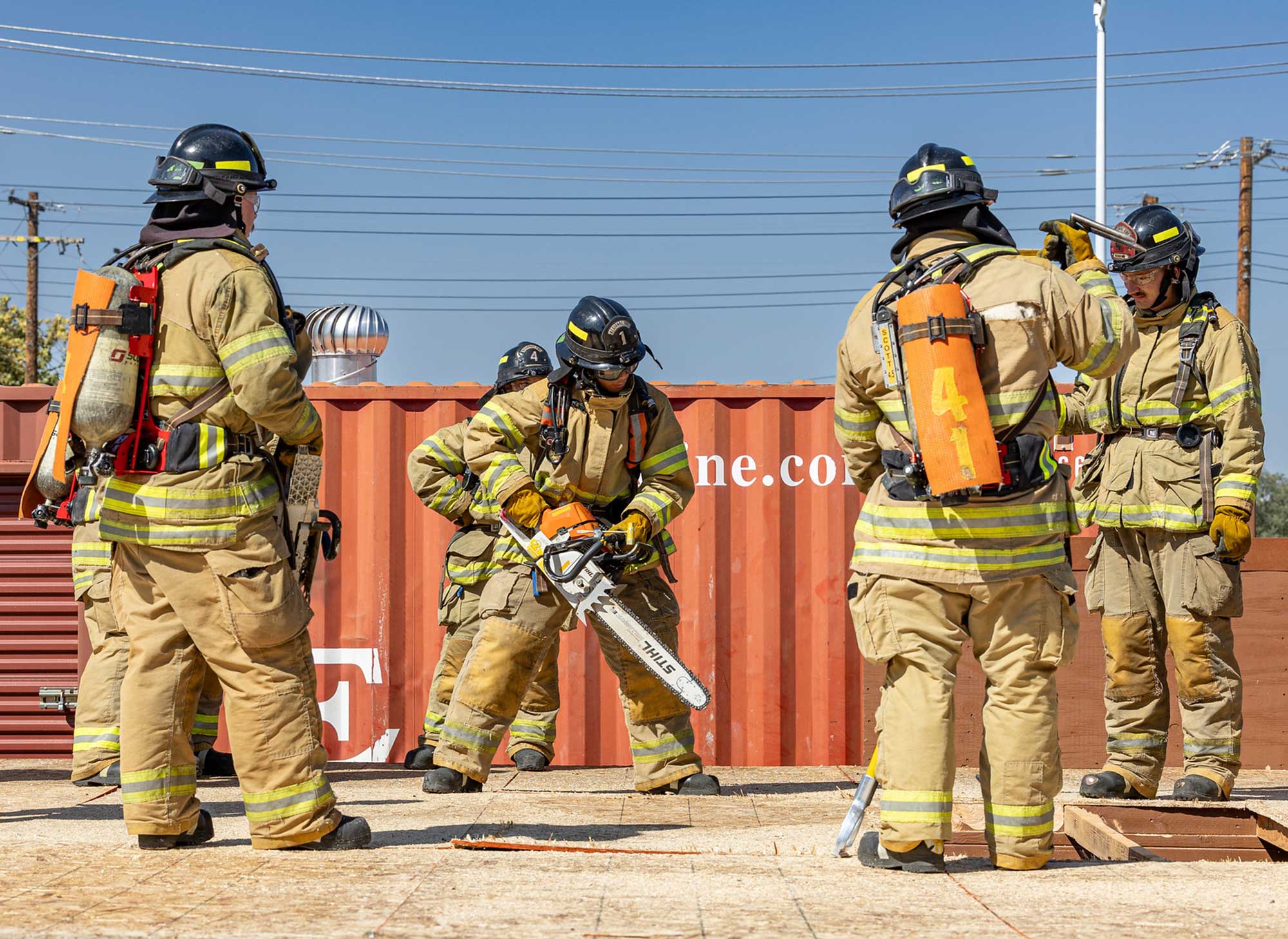 Fire academy student using chainsaw to practice opening house rooftop