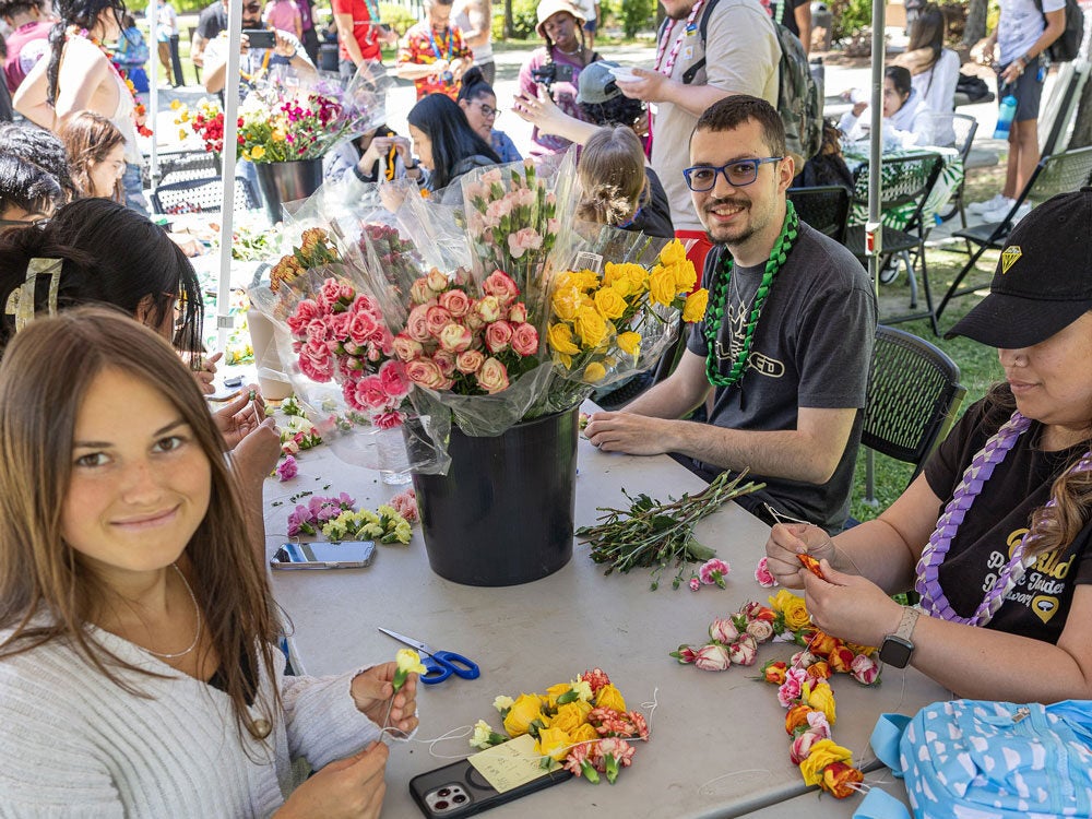 Students making leis using fresh flowers