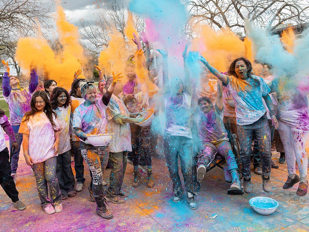 Students throw colorful chalk into the air to celebrate Holi Festival