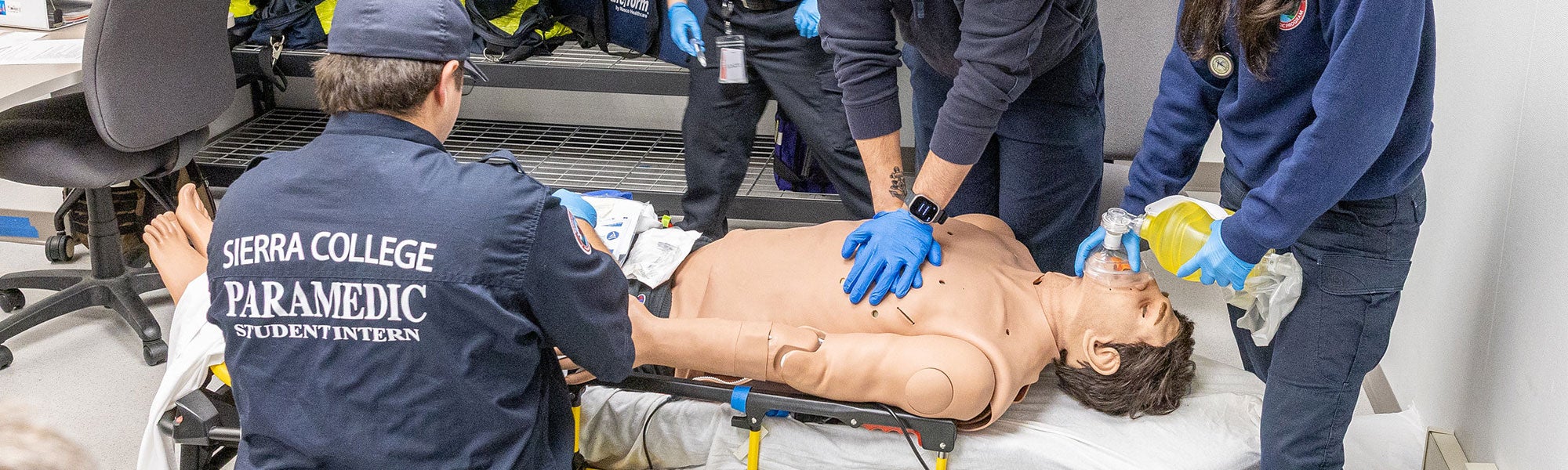 Students practicing compressions while placing patient on gurney for ambulatory transport.