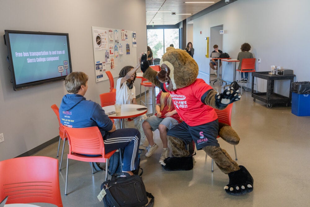 New Sierra College mascot, wearing a red shirt and black shorts, gives a 