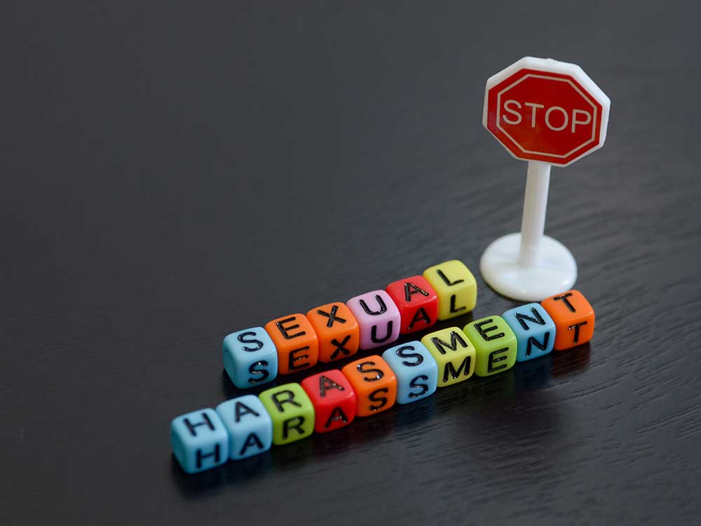 Colored letters spelling out sexual harassment next to a miniature stop sign