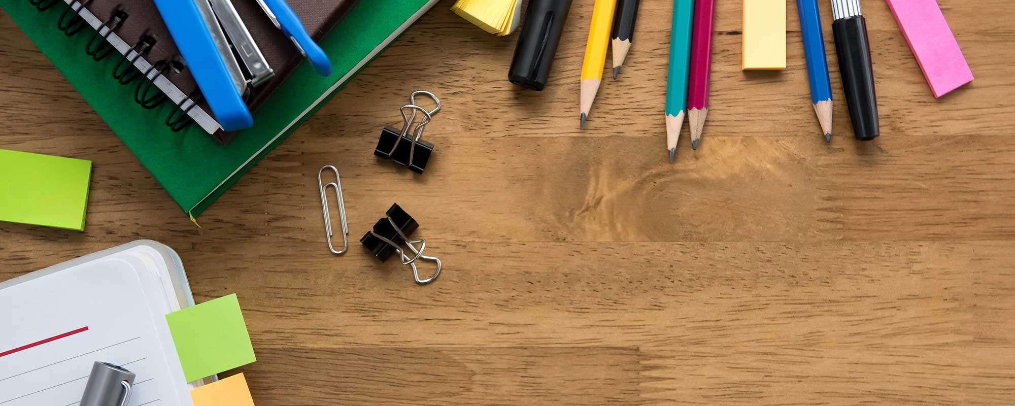 Pencils, pens, notepad on wood desk