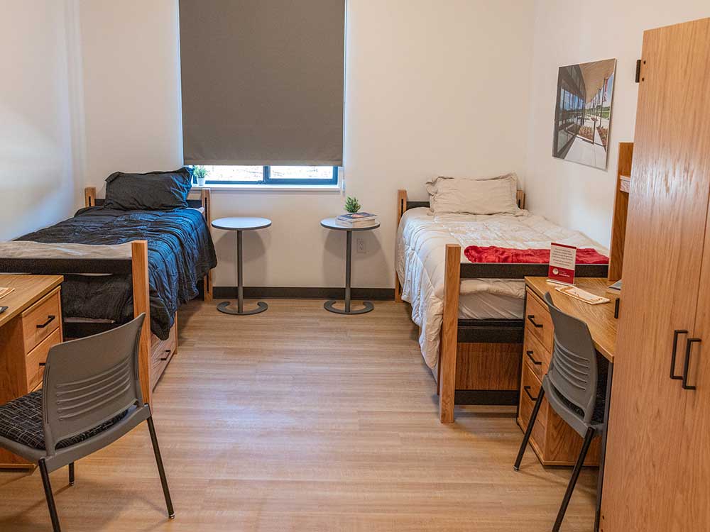 Student housing bedroom with two beds, two desks/chairs and closets