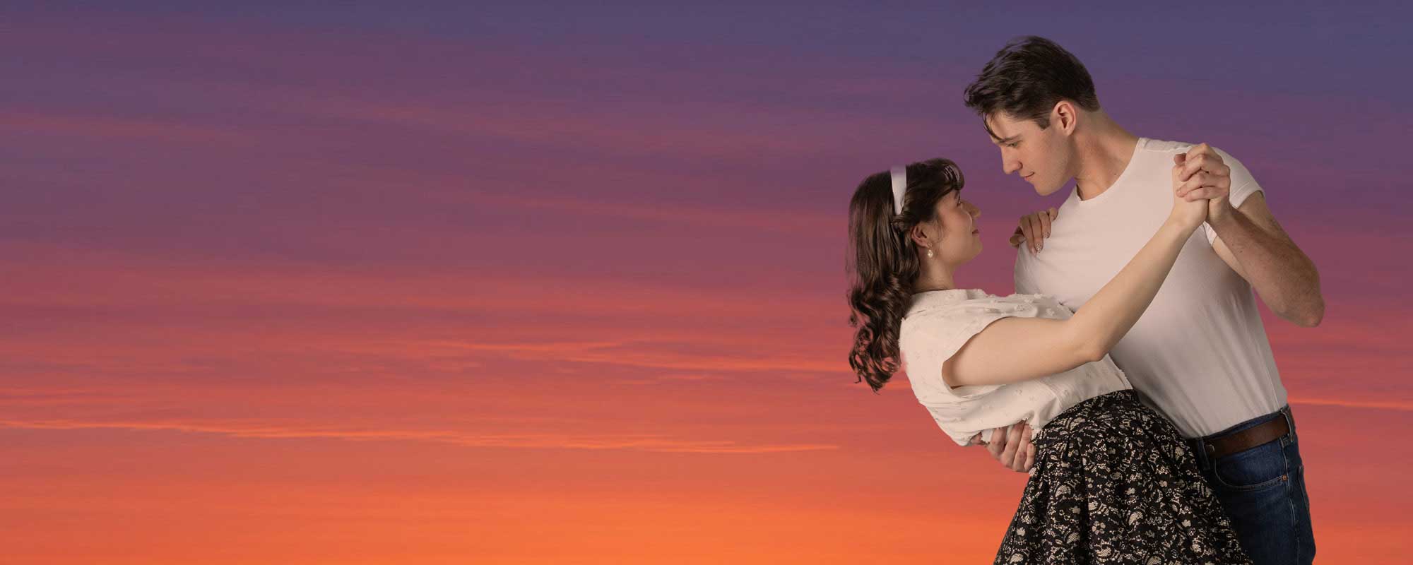 A woman being dipped by a man at sunset