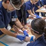 Phlebotomy instructor showing students how to take blood draw using oranges.